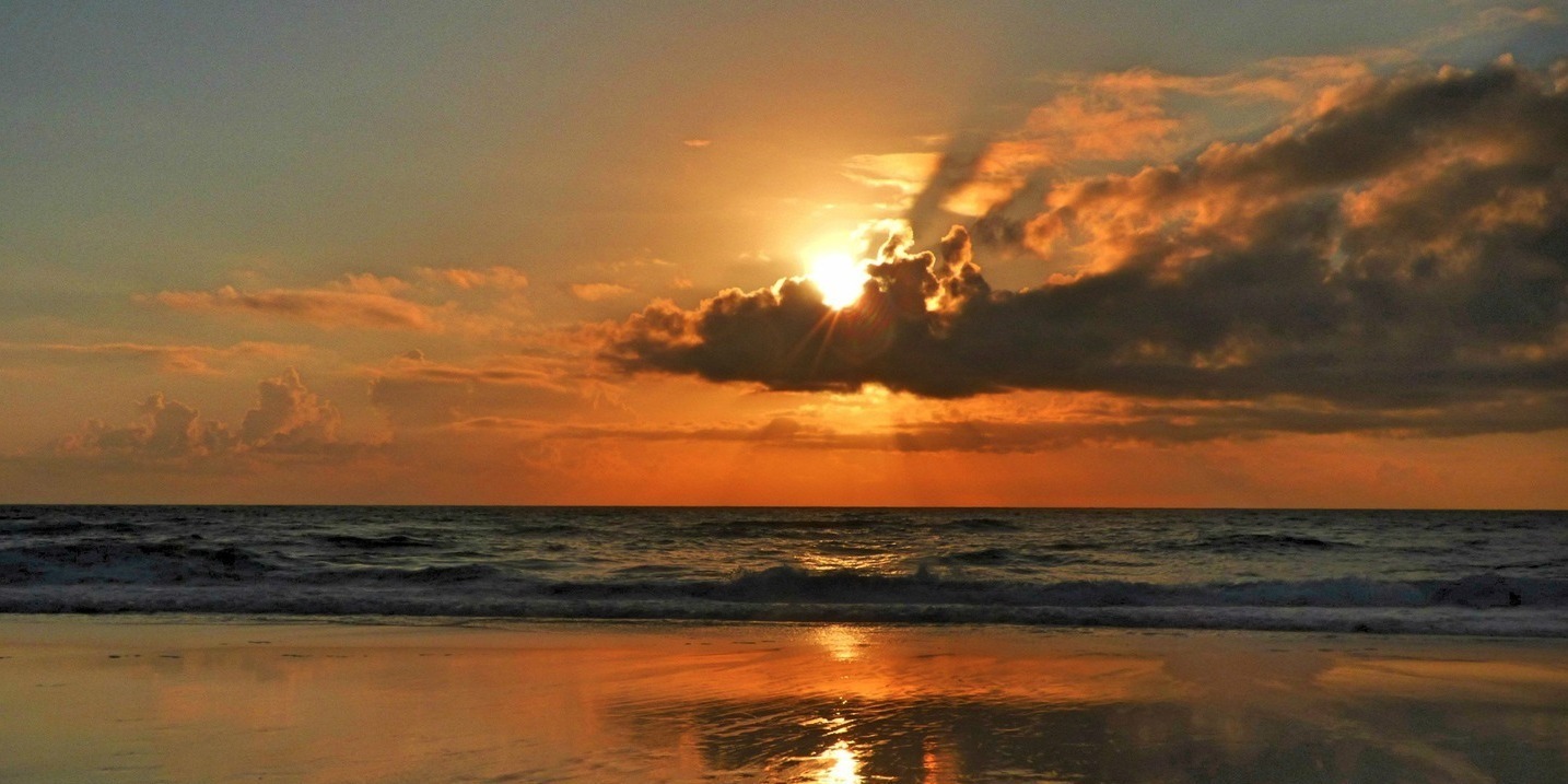Stunning golden sunset reflecting on the wet beach sand of the Portuguese coast.