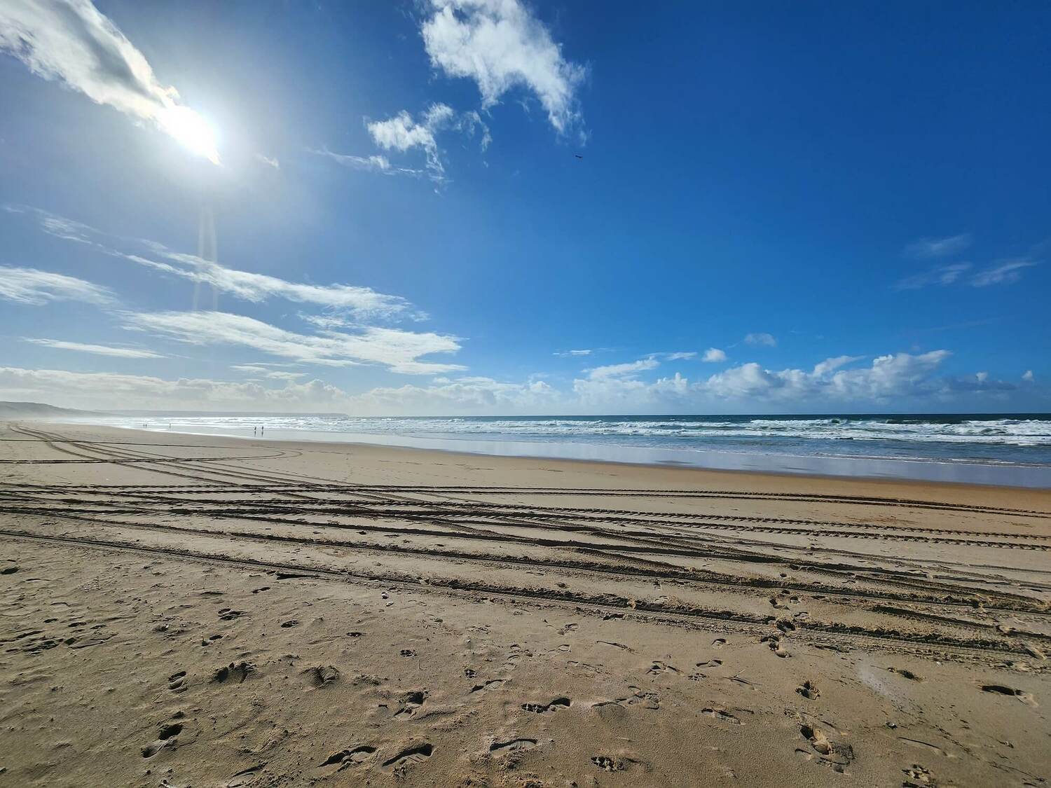 Wide sandy beach of Fonte da Telha under blue sky, a popular spot for private tours near Lisbon.
